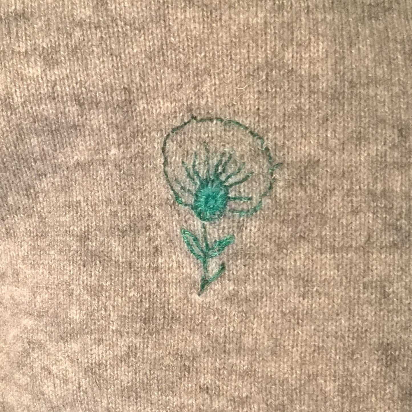Repair made on cashmere sweater using a cashmere patch and stick and stitch flower embroidery with silk thread. 