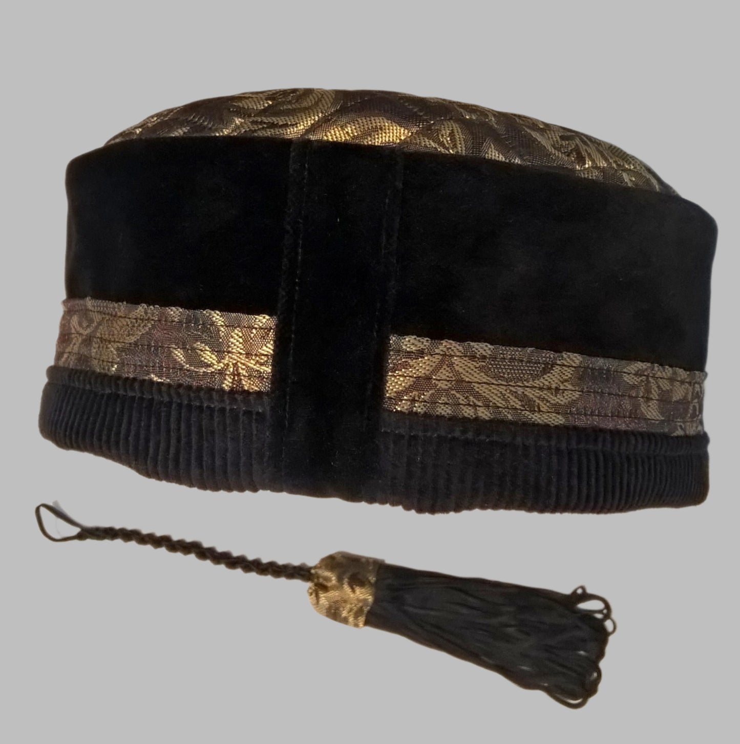 Back view of pillbox style smoking cap handmade in black velvet and corduroy, with gold brocade. Showing removable tassel