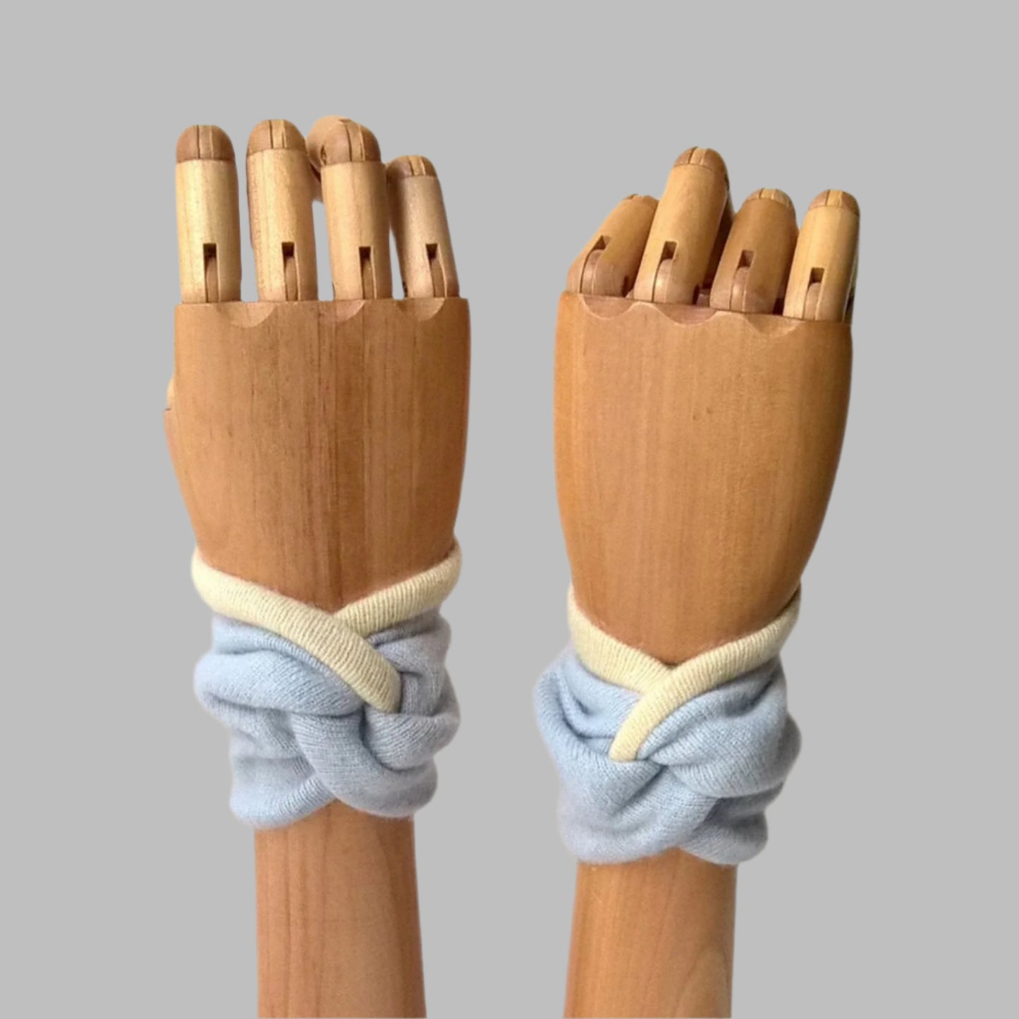 Twisted knot cashmere wrist warmer pulse point cuffs in pale blue and cream.