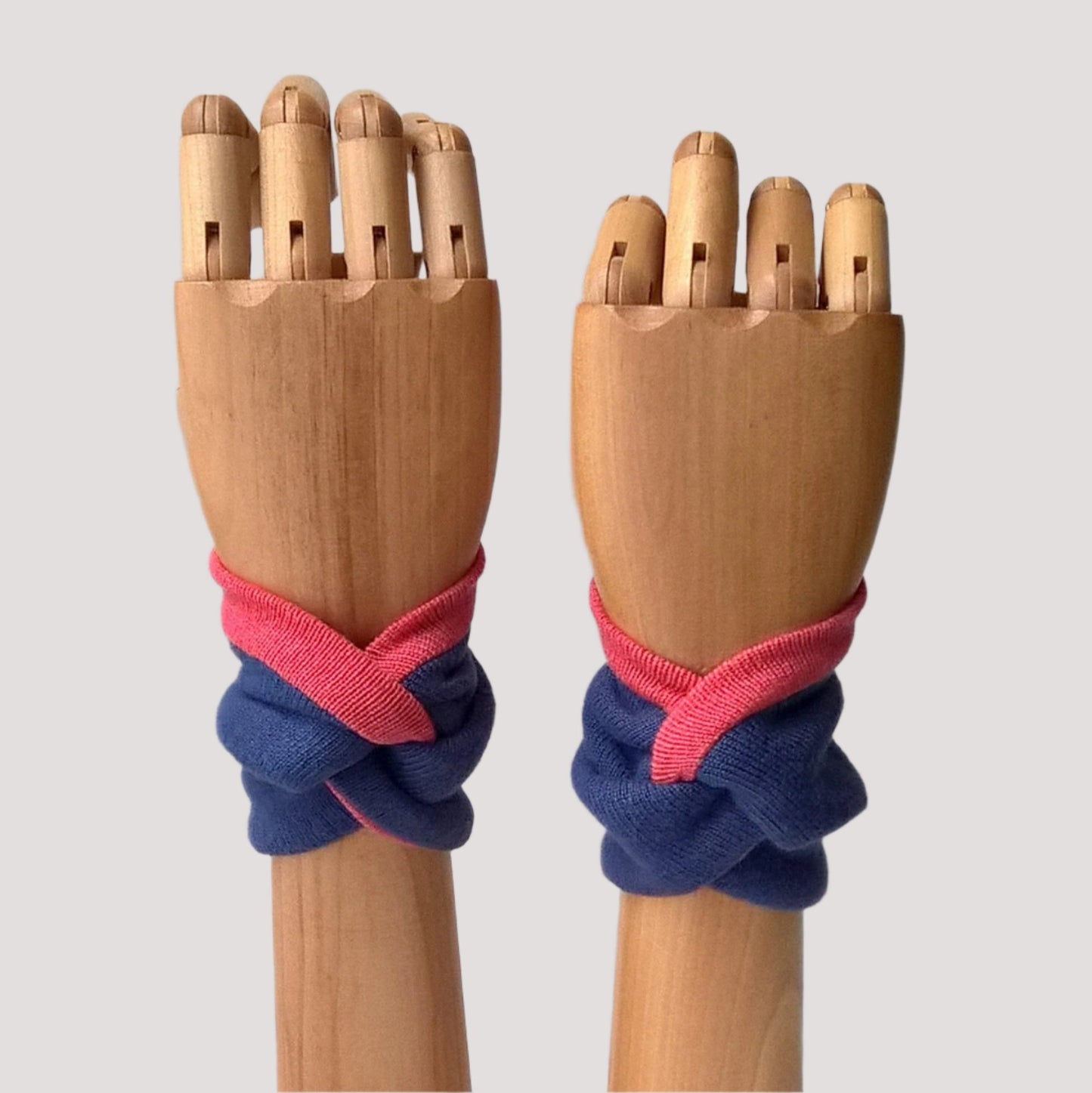 Twisted knot wrist warmer cuffs modeled on wooden arms