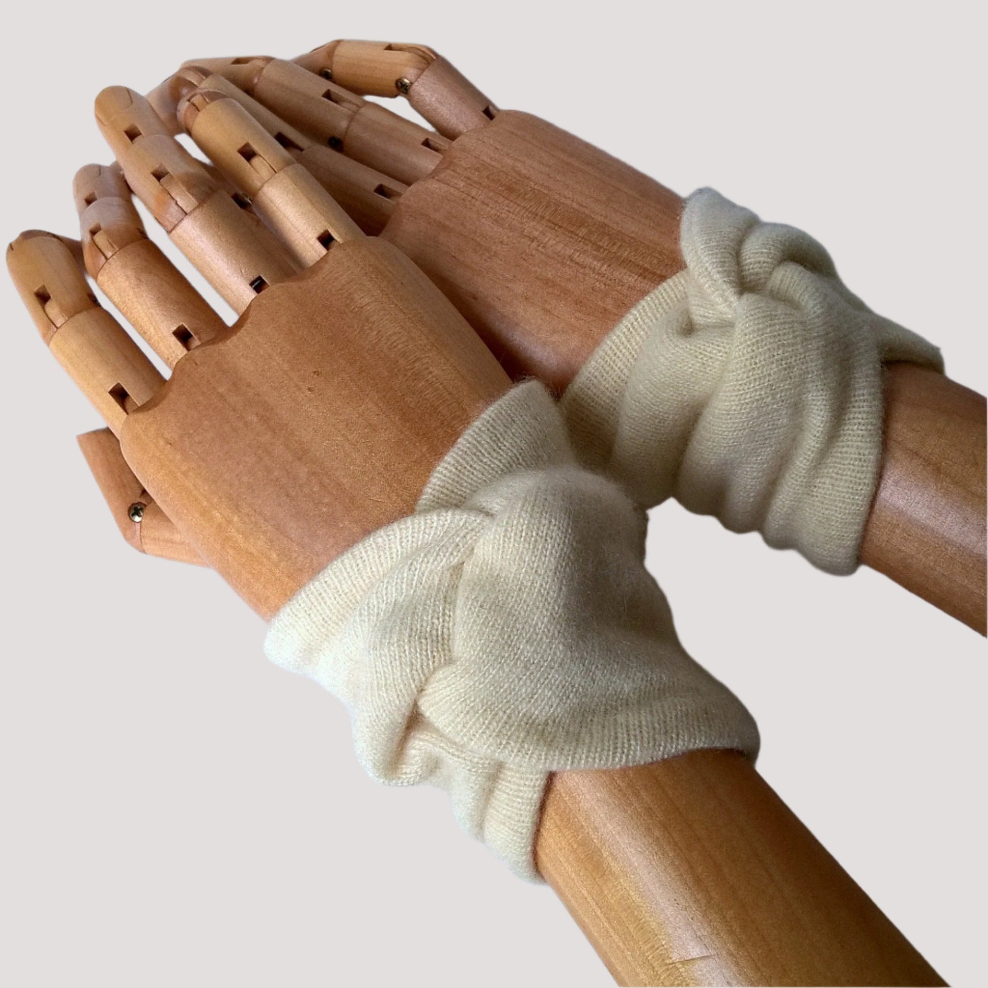 Short cream cashmere wrist warmers cover pulse points to raise body temperature, leaving hands free for everyday tasks