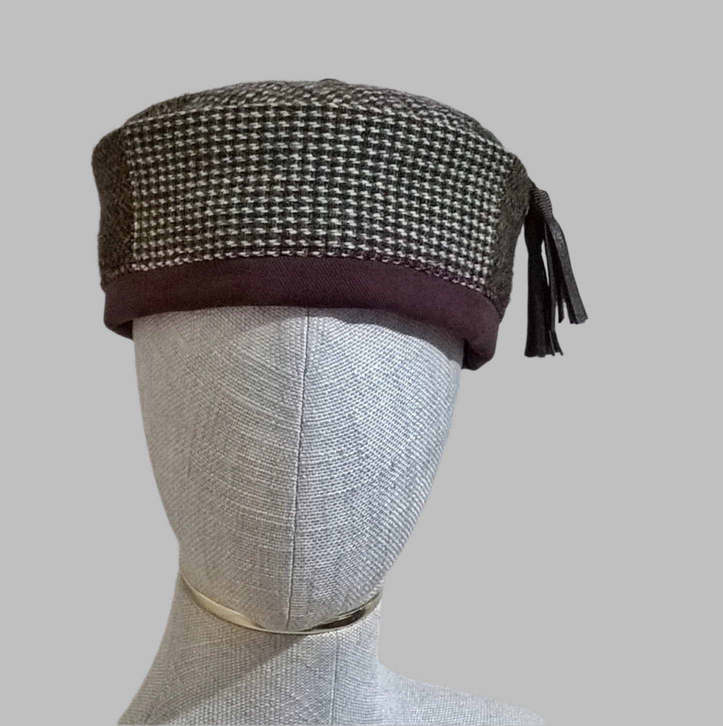 Patchwork Harris Tweed smoking cap with leather tassel in browns, maroon, and cream.