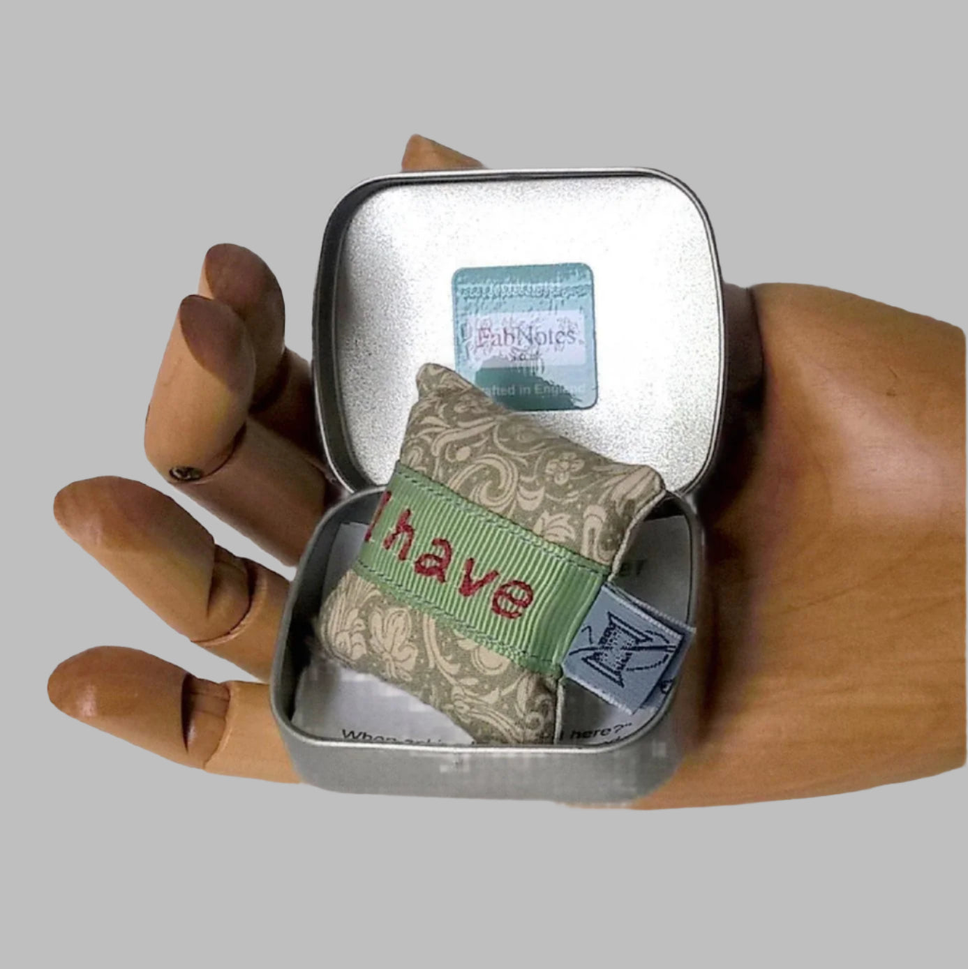 Mini lavender pillow in tin shown held in the palm of a hand