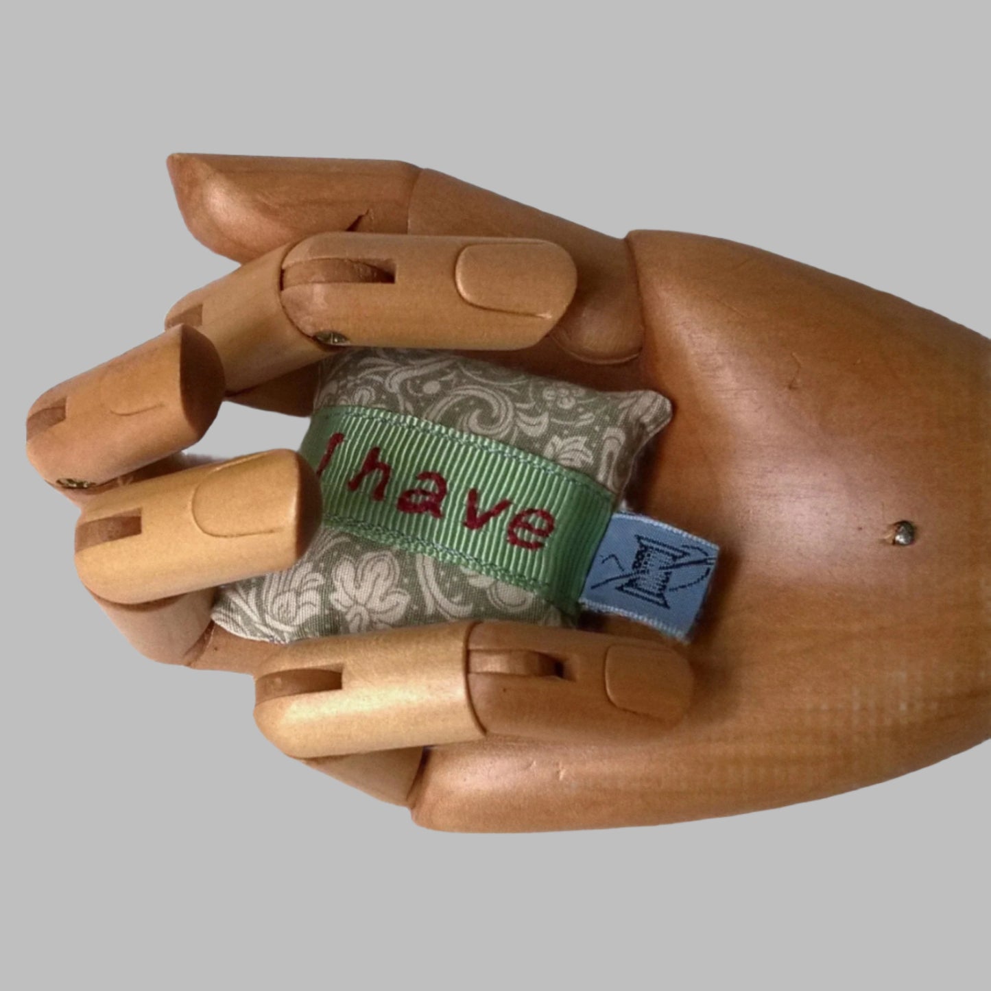 Mini embroidered lavender pillow shown held in the palm of a hand