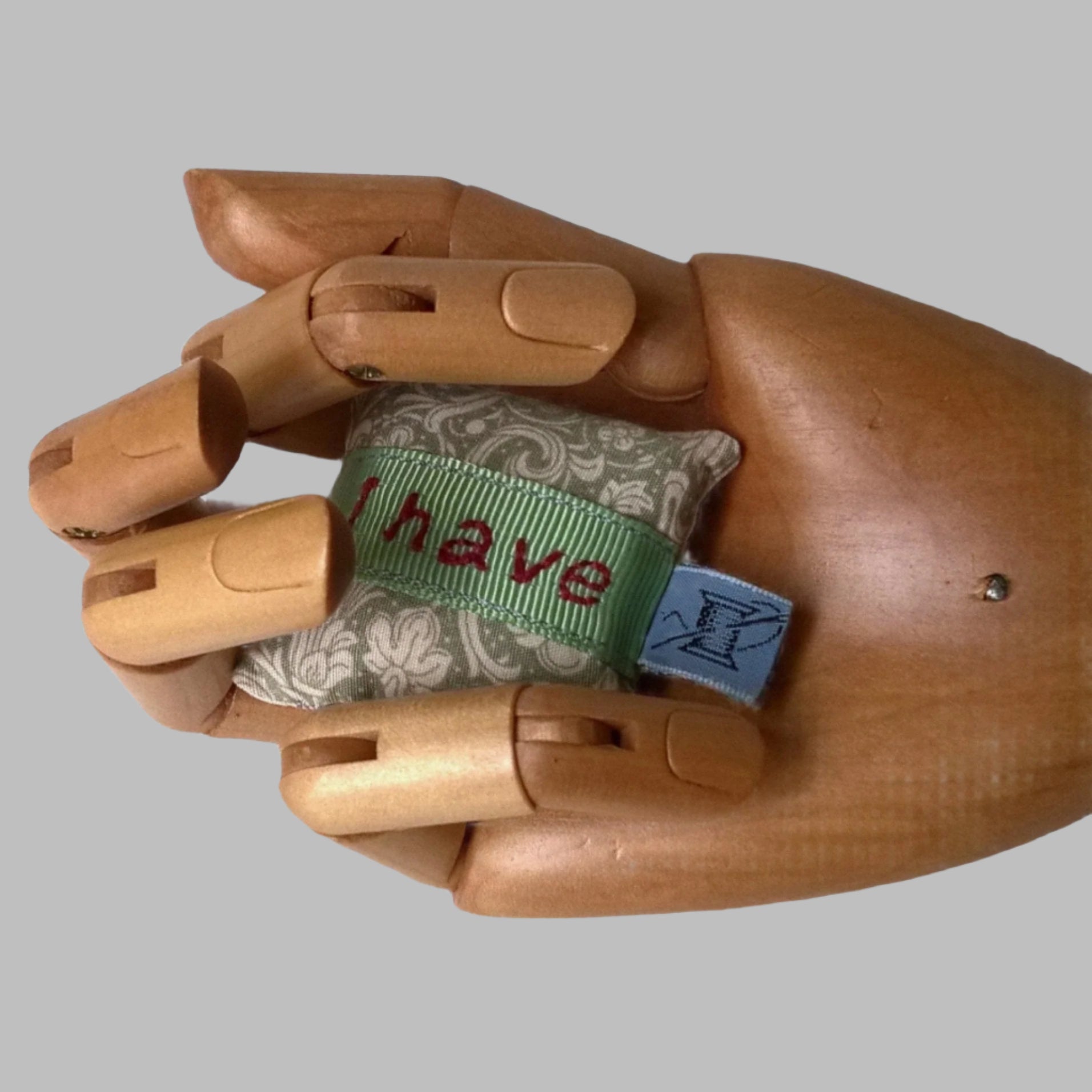 Mini embroidered lavender pillow shown held in the palm of a hand