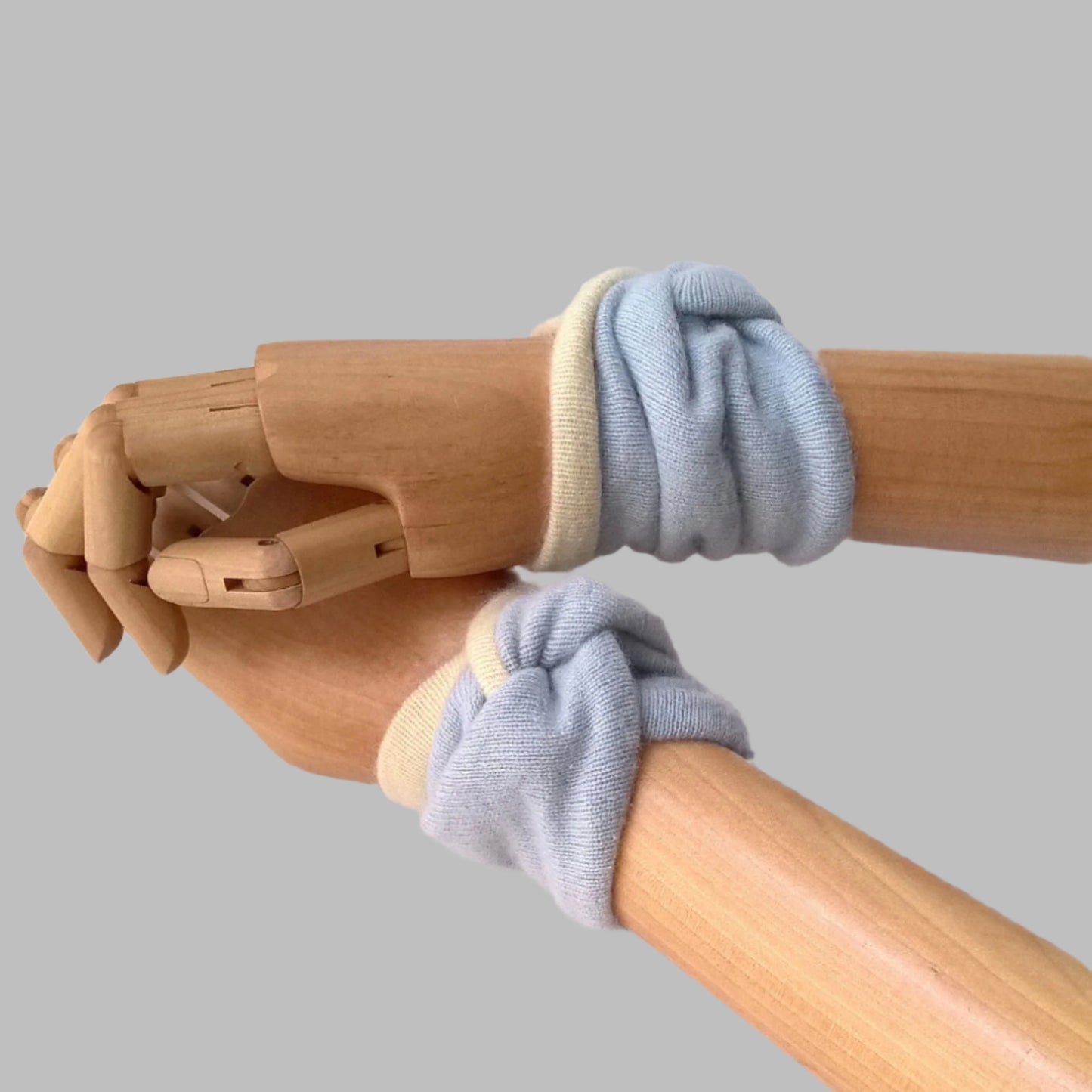 Twisted knot design pure cashmere wrist warmers, shown on mannequin arms.