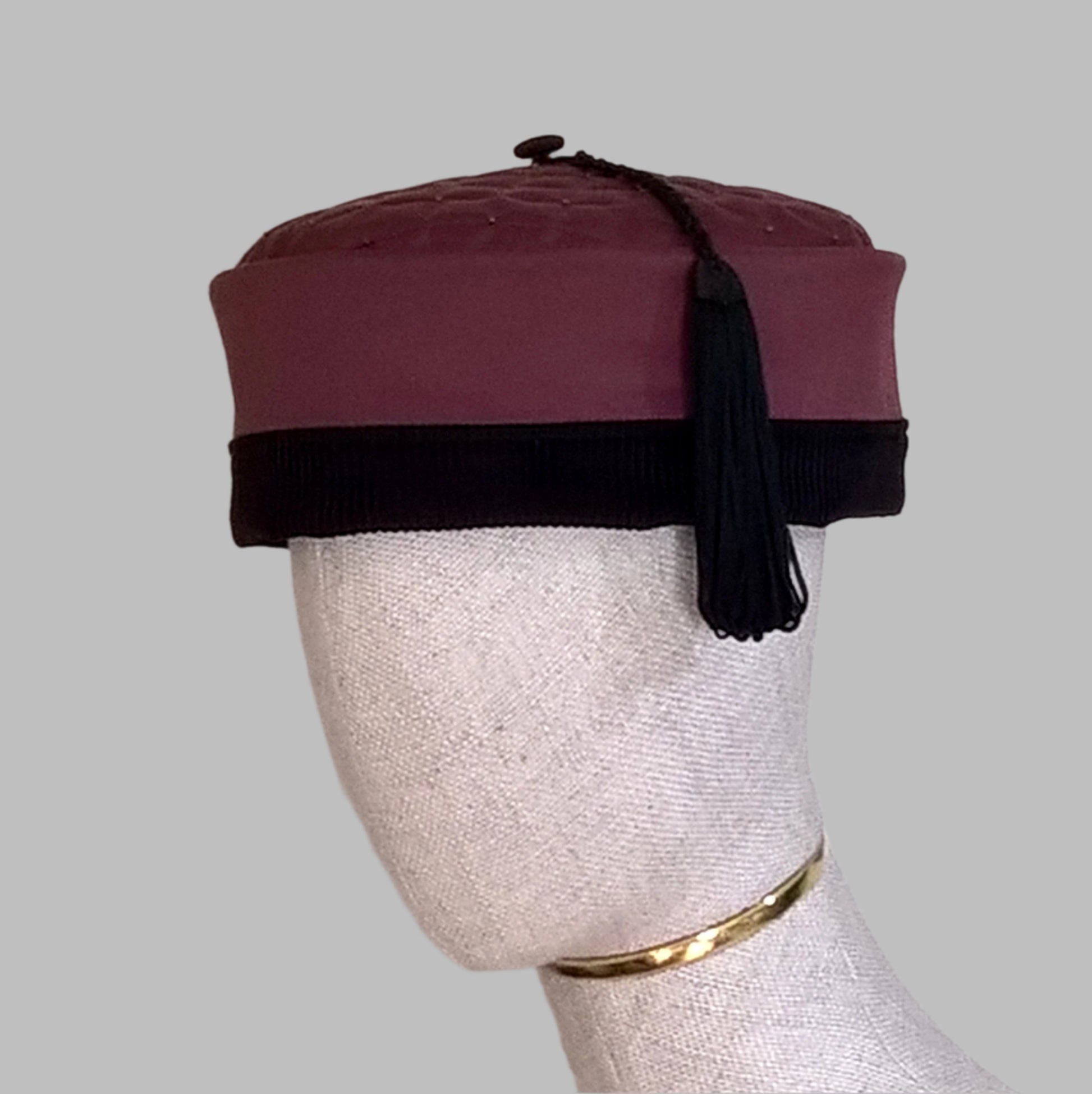 The beautiful maroon smoking cap is given a dramatic look the black corduroy edging and black tassel