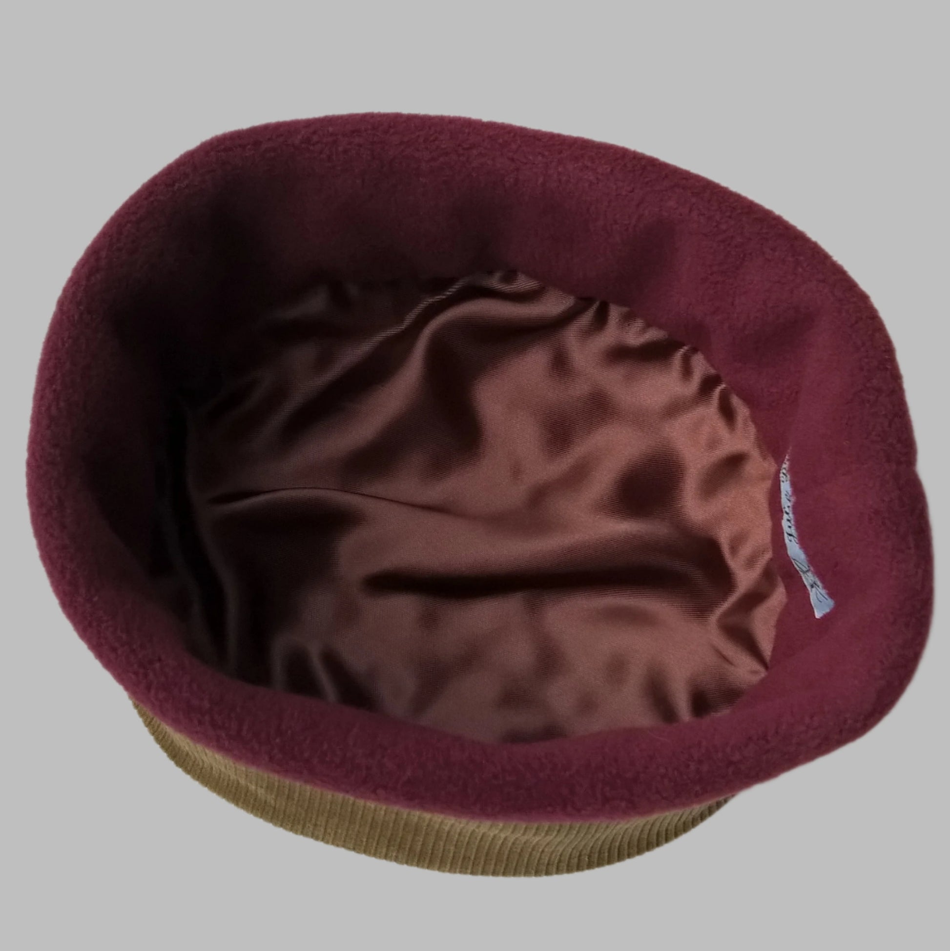 The hat is half lined with burgundy fleece and finished with chocolate brown satin