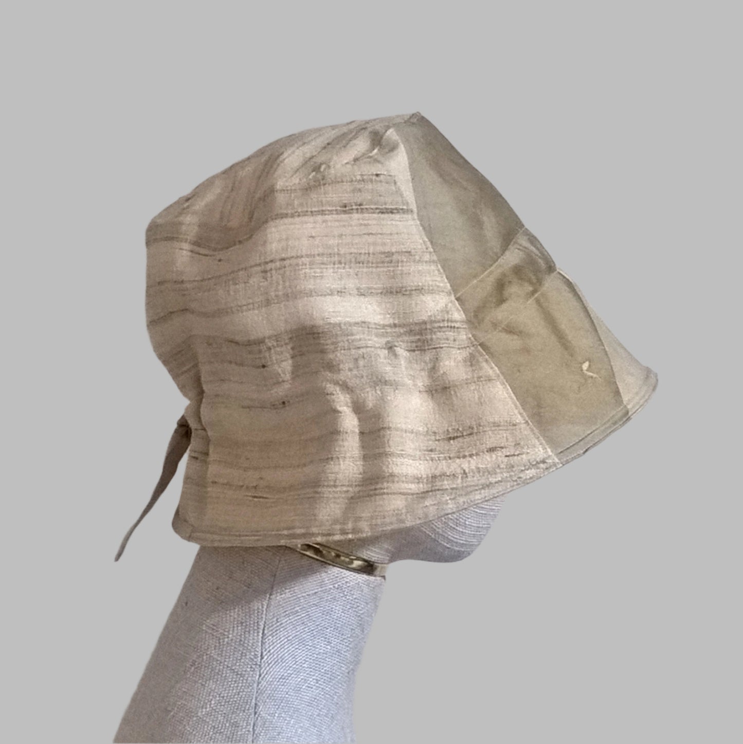 The bell shaped bucket hat has a bonnet style adjustable tie ribbon back