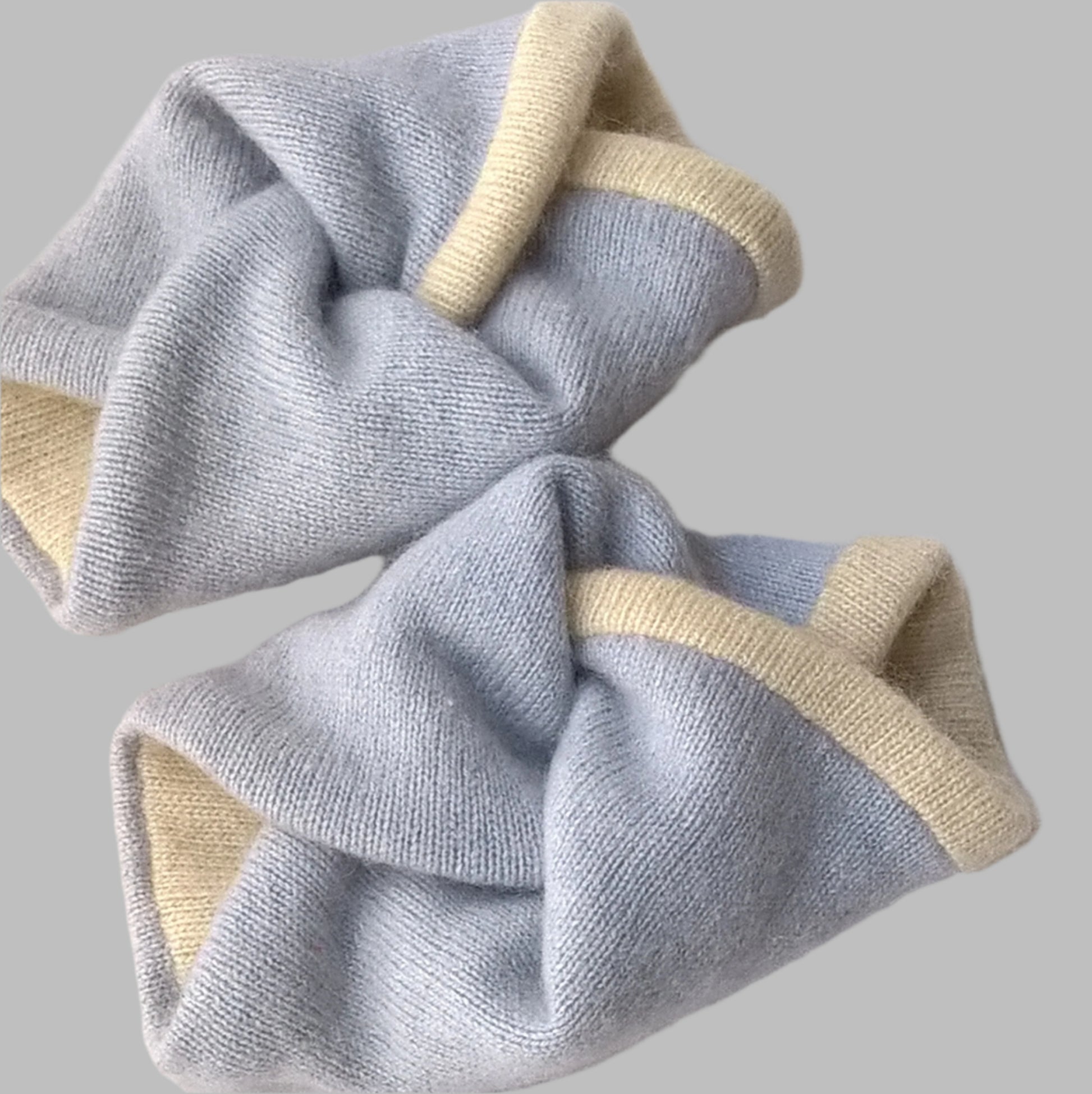 Cashmere wrist cuffs in a twisted knot design handmade in pale blue and cream